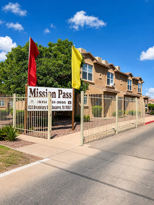 A sign for Mission Pass in front of a building.
