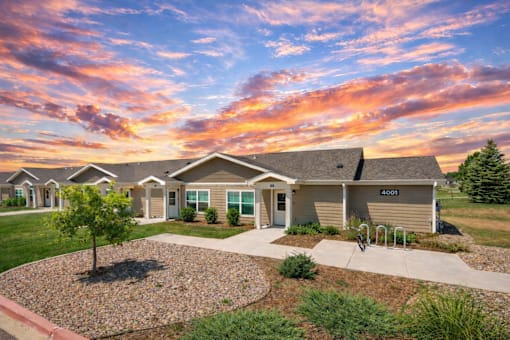 A row of houses numbered 4001 are shown in front of a beautiful sunset.