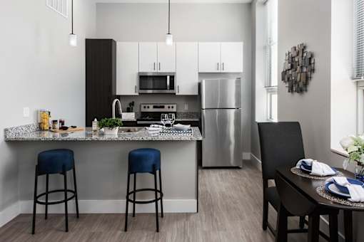A modern kitchen with a granite countertop and stools.