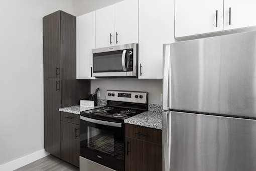 A modern kitchen with a stainless steel refrigerator, microwave, and oven.