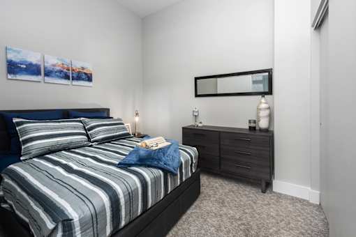 A bedroom with a bed, nightstand, and a painting on the wall.