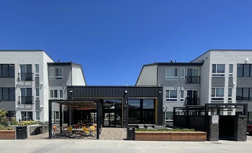 A modern building with a black and white exterior and a covered outdoor seating area.