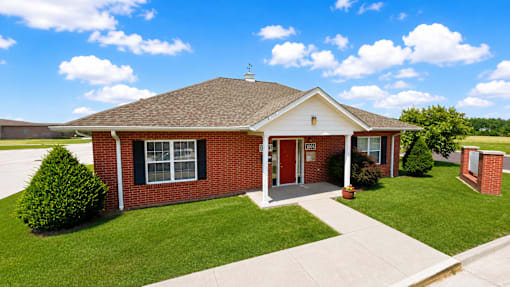 A small red brick house with a white door and windows.