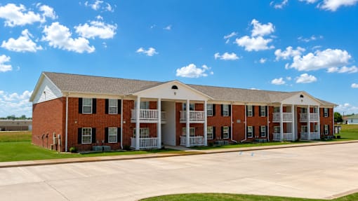 A red brick building with a white roof and a parking lot in front.