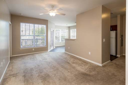 an empty living room with a ceiling fan and a window