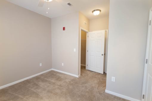 a room with a carpeted floor and a door to a closet