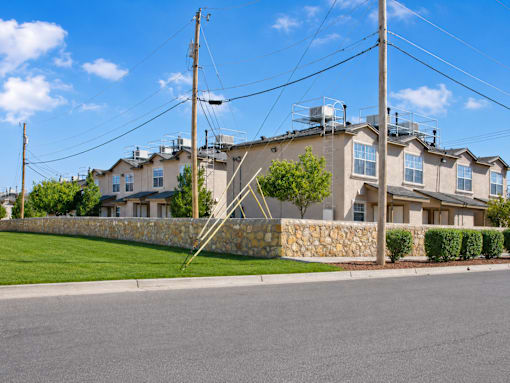 A row of houses with a stone wall in front.