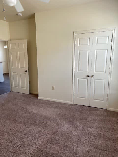 A room with two white doors and a ceiling fan.