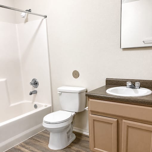 A white toilet sits next to a white shower curtain in a bathroom.
