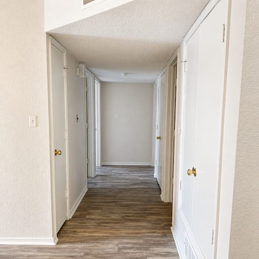A long hallway with white walls and wood floors.