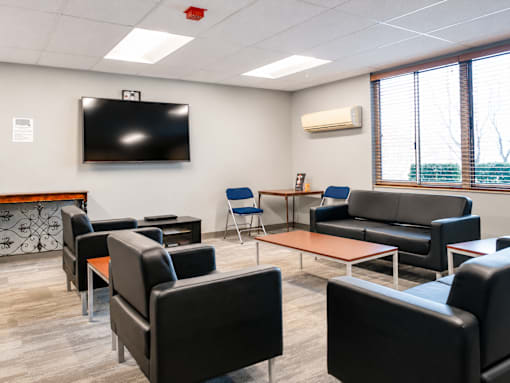 A conference room with a television on the wall and comfortable seating.