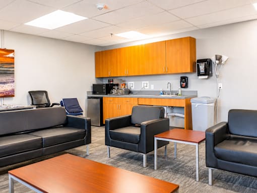 A modern office break room with a kitchenette and comfortable seating.