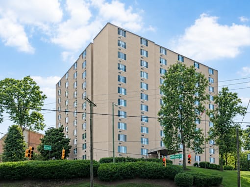 A large beige building with many windows and trees in front.