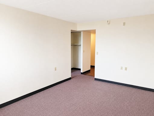 A room with a carpeted floor and a doorway leading to another room.