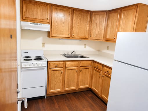 A kitchen with wooden cabinets and a white refrigerator.