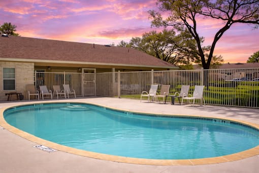 A small pool in a backyard with a sunset in the background.