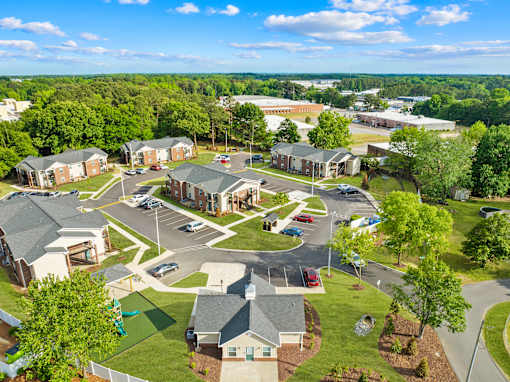 A bird's eye view of a residential area with houses and a parking lot.