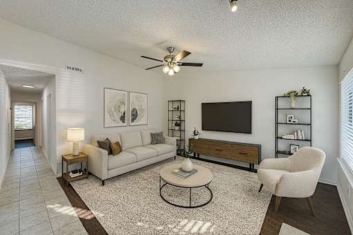 A living room with a white couch, a coffee table, and a television.