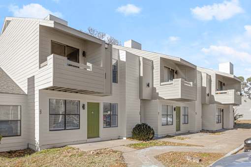 A modern white building with green doors and windows. at Osage Creek, Rogers, AR