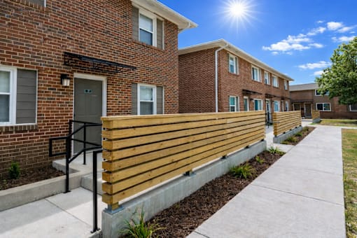 A sunny day at a brick apartment complex with a wooden fence.