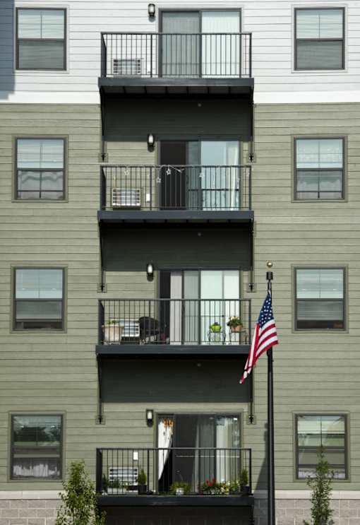 A building with a balcony and an American flag on a pole.