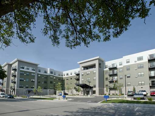 A large apartment complex with a parking lot in front.