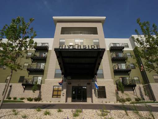 The Riverside building has a modern design with balconies on the second floor.