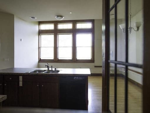 A kitchen with dark wood cabinets and a sink under a window.