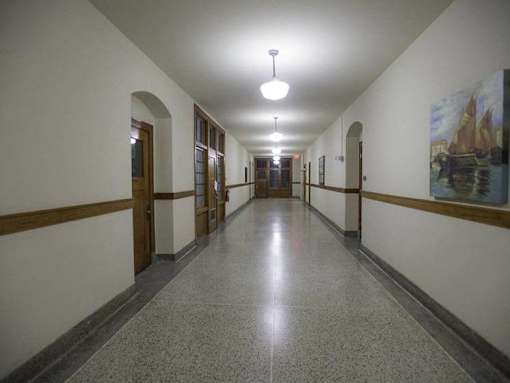 A long hallway with doors on both sides and a painting on the wall.