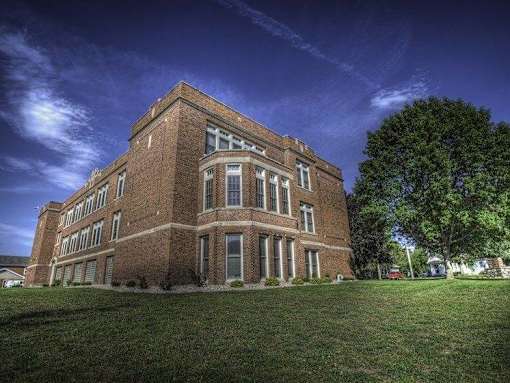 A large red brick building with a green lawn in front.