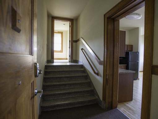 A hallway with a staircase and a door on the left.