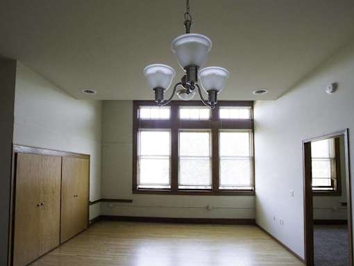 A room with a large window and a chandelier hanging from the ceiling.