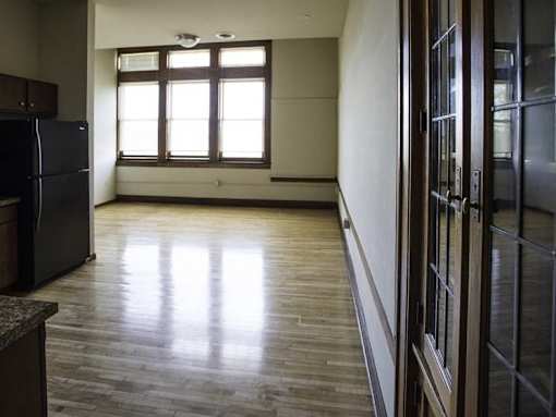 A kitchen with a black fridge and wooden floors.