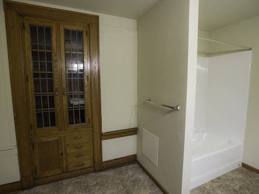 A bathroom with a wooden door and a white bathtub.