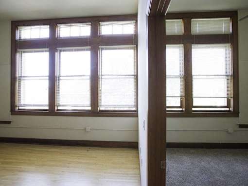 A room with two windows and a carpet on the floor.