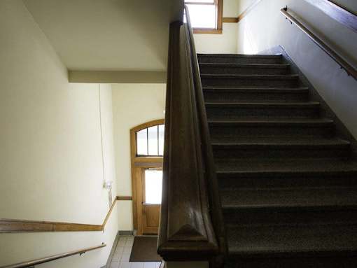 A staircase with a wooden handrail and a door at the bottom.