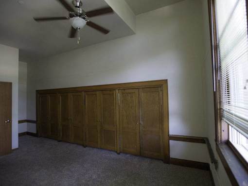 A room with a ceiling fan and a row of wooden doors.