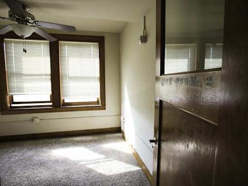 A room with a ceiling fan and a window with blinds.