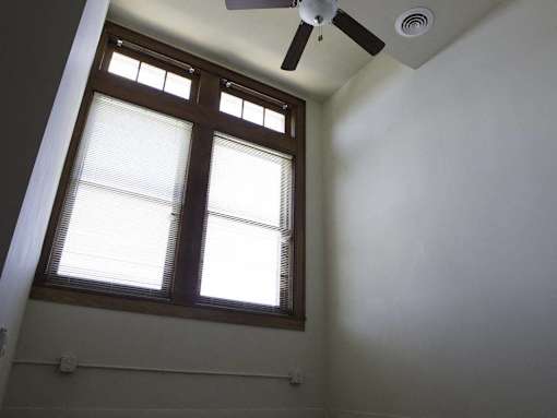 A window with blinds and a ceiling fan in a room.