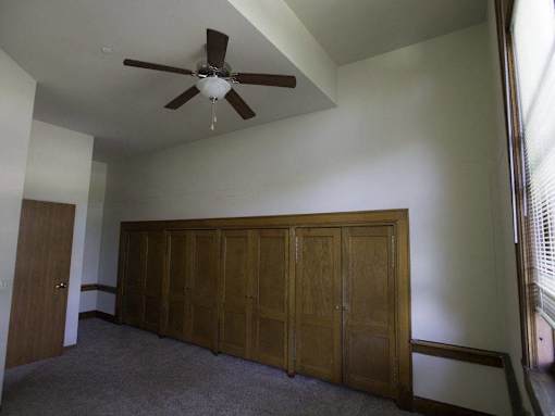 A room with a ceiling fan and a large wooden wardrobe.