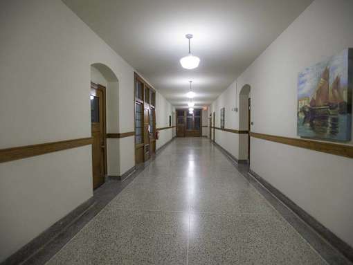 A long hallway with a light on the ceiling and a painting on the wall.