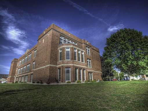 A large red brick building with a green lawn in front.
