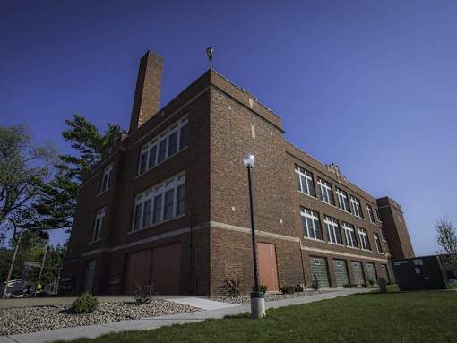 A large brick building with a red door and a chimney.