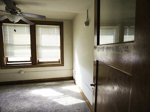 A room with a ceiling fan and a window with blinds.