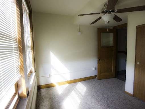 A room with a ceiling fan and a door.