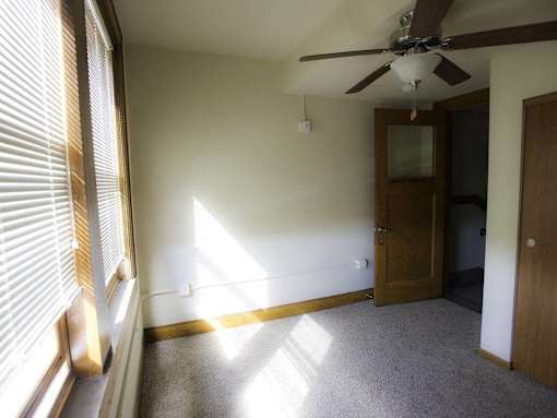 A room with a ceiling fan and a door.