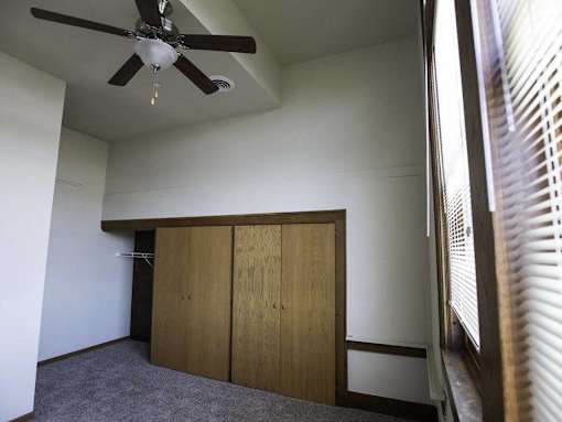 A room with a ceiling fan and a window with blinds.