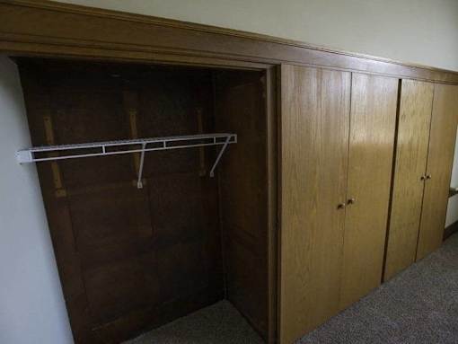 A wooden closet with a shelf and two doors.