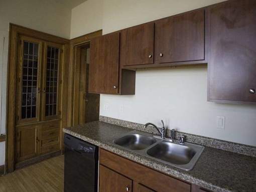 A kitchen with a black dishwasher and a sink with a granite counter top.
