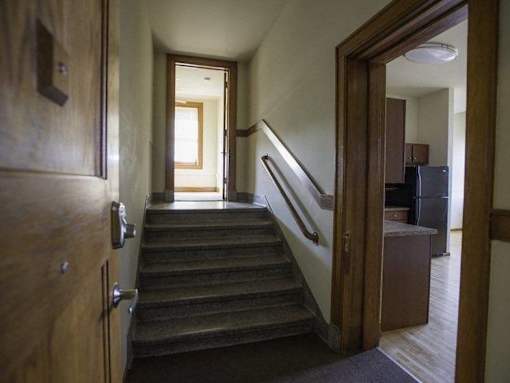 A hallway with a staircase leading to a second floor.